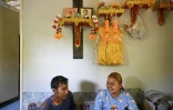Pirun Kla-Talay et son épouse Janjira Khampradit assis dans leur maison sous les portraits des parents de Pirun, morts dans le tsunami de 2004, le 19 novembre 2024 dans la province de Phang Nga, le 19 novembre 2024 en Thaïlande