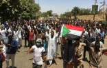 Des manifestants soudanais brandissent le drapeau du Soudan en marchant vers le QG de l'armée à Khartoum, le 8 avril 2019