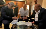 Une photo fournie par le parti arabe israélien Raam montre le chef du parti Mansour Abbas (D) signer l’accord de coalition avec le chef de l’opposition Yaïr Lapid (G) et le chef de la droite radicale Naftali Bennett (centre) à Ramat Gan, près de Tel-Aviv, le 2 juin 2021
