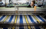 Une employée surveille la fabrication d'un "tartan pour l'Ukraine", aux couleurs du drapeau ukrainien, dans l'atelier de la société Great Scot, le 29 avril 2022 à Keith, en Ecosse