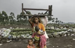 Une femme déplacée avec ses enfants transporte quelques biens récupérés dans la zone où se trouvait autrefois un camp de personnes déplacées avant sa destruction, à Goma le 1er février 2025
