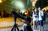 Une manifestante regarde dans un télescope pendant une manifestation en forme de spectacle laser, le 7 août 2019 à Hong Kong