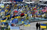 Un couple devant des drapeaux et des portraits de soldats au mémorial improvisé pour les combattants ukrainiens et étrangers tombés au combat, sur la place de l'Indépendance à Kiev, le 19 avril 2025 en Ukraine
