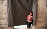 Un enfant syrien devant le rideau qui fait office de porte d'entrée aux chambres de déplacés syriens qui ont trouvé refuge dans une cave dans la ville d'Al-Bab (nord syrien), le 7 décembre 2018