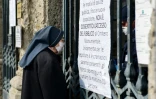 Une religieuse devant la porte d'entrée du cimetière Monumental de Bergame, fermé, le 20 mars 2020