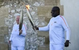 L'ancien footballeur français Basile Boli (d) allume le flambeau de Colette Cataldo, supportrice historique de l’OM dans le cadre des relais de la flamme olympique et paralympique à la basilique Notre Dame de la Garde, à Marseille, le 9 mai 202
