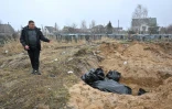Un homme se tient près d'une fosse commune à Boutcha, près de Kiev, le 3 avril 2022