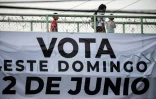 Une affiche appelant les Mexicains à voter dimanche 2 juin est attachée à un pont pour piétons sur lequel passe une femme et deux enfants dans le district de Xochimilco à Mexico le 31 mai 2024