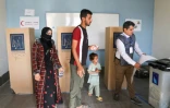 Un Irakien déplacé reçoit de l'aide pour voter dans un bureau de vote avant les élections législatives du 11 novembre, dans un camp du nord de l'Irak, le 9 novembre 2025