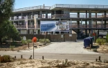 Un panneau d'affichage fait la promotion d'un "complexe de plage et de golf" devant un bâtiment en construction à Comporta,le 29 septembre 2025 au Portugal