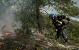 Un pompier ukrainien répand du sable sur un feu causé par des bombardements, à Sydorovié (est de l'Ukraine), le 17 mai 2022