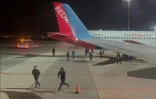 Sur cette capture d'écran d'une vidéo publiée sur la chaîne Telegram de @askrasul le 29 octobre 2023, des manifestants courent au niveau de l'aire de stationnement de l'aéroport de Makhatchkala, en Russie