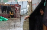 Un Palestinien sous la pluie dans un camp de fortune pour les déplacés à Khan Younès, dans le sud de la bande de Gaza, le 31 décembre 2024