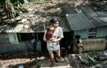 L'artiste de rue Ari Munandar et sa fille devant leur maison à Jakarta, le 7 avril 2025 en Indonésie