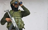 Un membre du personnel paramilitaire indien assure une surveillance à l'aide de jumelle en haut d'un bâtiment commercial à Srinagar, le 5 mai 2025 au Cachemire indien