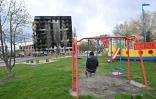 Un adolescent assis dans une balançoire observe un immeuble d'habitations détruit par des bombardements dans la ville de ukrainienne de Borodianka, dans la région de Kiev, le 17 avril 2022