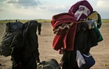 Des femmes croulant sous de lourds sacs à dos et baluchons fuient le dernier réduit du groupe Etat islamique (EI) à Baghouz dans l'est de la Syrie, le 6 mars 2019