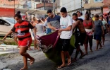 Des habitants portent un cadavre lors d'une opération policière dans la favela Complexo do Alemao à Rio de Janeiro, le 21 juillet 2022
