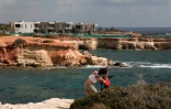 Une touriste prend en photo le 9 mai 2018 six villas de luxe en construction à proximité des grottes marines où ont élu domicile des phoques moines, les mammifères les plus menacés de Méditerranée. Ces villas ont engendré de nombreuses protestations des défenseurs de l'environnement