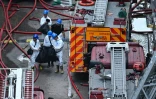 Des policiers de l’unité d’identification des victimes de catastrophes, vêtus de combinaisons intégrales de protection blanches, transportent des sacs devant le complexe résidentiel de Wang Fuk Court à Hong Kong  la suite de l’incendie meurtrier survenu trois jours auparavant