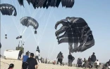Capture d'écran d'une video AFPTV de Palestiniens qui courent en direction de parachutes transportant des colis de nourriture larguée par des avions américains sur un plage de la bande de Gaza le 2 mars 2024