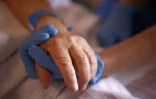 Un personnel soignant tient la main d'un patient en soins palliatifs, à l'hôpital Eugénie d'Ajaccio, le 23 avril 2020