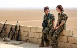 Chirine (G) et Kazîwar (D), membres des Unités de protection de la femme kurde (YPJ) discutent sur le toit d'une maison du village syrien de Mazraat Khaled, à environ 40 km de de Raqa, le 9 novembre 2016
