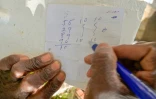Un Cubain montre sur un bout de papier les numéros qu'il va jouer à la "bolita", la loterie clandestine, à La Havane, le 14 avril 2025