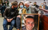 Didier (D), Cécile (C) et Quentin Noyer (G), parents et frère du caporal Arthur Noyer montrent un portrait de la victime aux assises de Chambéry, le 3 mai 2021