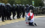 Une femme se met à genoux devant les policiers pendant une manifestation contre la réélection controversée du président Alexandre Loukachenko le 13 septembre 2020 à Minsk