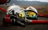 Deux casques de pompier et une lance à incendie gisent au sol alors qu'un incendie de forêt fait rage à Saint-Jean-d'Illac, à environ 30 km de Bordeaux, le 26 juillet 2026