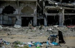 Une femme pousse un fauteuil roulant au milieu d'immeubles détruits dans le nord de la bande de Gaza le 21 mars 2024