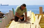 Le Syrien Khaled Bahlawan construit à la main un bateau en bois au bord de l'île d'Arwad, dans l'ouest de la Syrie, un artisanat que sa famille veut préserver, le 24 juillet 2022
