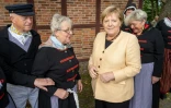 La chancelière allemande Angela Merkel en compagnie de femmes en costume traditionnel lors de sa visite du village de pêcheurs de Waase, sur l'île de Unmanz, nord-est de l'Allemagne, le 21 septembre 2021