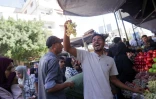 Un vendeur brandit une grappe de raisins sur un marché à Deir el-Balah, dans le centre de la bande de Gaza, plus d’une semaine après l’entrée en vigueur d’un accord de cessez-le-feu entre Israël et le Hamas, le 18 octobre 2025