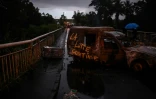 Des personnes passent devant un barrage routier composé de véhicules brûlés et de débris pour se rendre à Sainte-Rose (Guadeloupe), le 30 novembre 2021