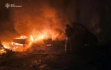 Photo prise et diffusée par les services d'urgence ukrainiens, le 23 décembre 2025, montrant un secouriste ukrainien luttant contre un incendie après une frappe de drone russe dans la région de Tchernihiv
