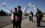 Des touristes chinois se prennent en photo devant un monument à Pyongyang, le 14 avril 2019 en Corée du Nord