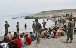 Des soldats espagnols gardent des migrants arrivés à la nage à l'enclave espagnole de Ceuta, le 18 mai 2021