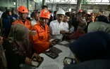 Mohammad Syafii (C), chef de l'Agence nationale de recherche et de sauvetage de l'Indonésie, accompagné de Saifullah Yusuf (centre D), ministre des Affaires sociales, inspecte une distribution de nourriture pour les proches des écoliers portés disparus après l'effondrement de l'école religieuse islamique Al Khoziny à Sidoarjo, dans la province de Java oriental, le 1er octobre 2025