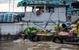 Une marchande de légumes propose ses produits aux habitants d'une maison-bateau sur le marché flottant de Cai Rang, dans le delta du Mékong, le 17 juillet 2017