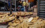 Des poissons sont placés dans un panier pour sécher au bord de la route, devant une boutique de produits séchés à Hong Kong le 29 mars 2016