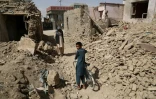 Des Afghans marchent le 16 août 2018 près de maisons détruites à la suite d'une attaque des talibans à Ghazni