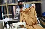Un couturier montre une dishdasha, robe traditionnelle portée par les hommes à Oman, dans un magasin de Mascate, le 10 janvier 2022