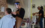 Andy Adkins (g) et Andy Jupp coupent les cheveux de leurs clients dans leur salon de Brighton, le 4 juillet 2020