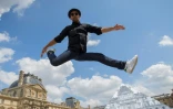 L'artiste et photographe français JR saute devant la Pyramide du Louvre à Paris le 25 mai 2016

