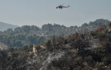 Un hélicoptère Sikorsky S-64 Skycrane survole une propriété ravagée par un incendie dans le village de Ziria, près de Patras, le 1er août 2021