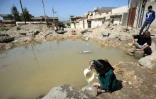 Des habitants de Mossoul remplissent des bidons d'eau, le 6 avril 2017 en Irak
