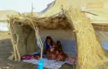 Une femme et ses enfants déplacés à l'ombre d'une hutte dans un camp à Gadaref, dans l'est du Soudan, le 20 mars 2024
