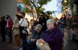Des personnes portant des masques tiennent des bougies lors d'un hommage aux victimes du coronavirus le 20 mars 2021 dans le quartier de Little Tokyo Ă Los Angeles, Californie